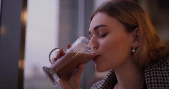 Beautiful Woman Drinks Cacao in Cafe