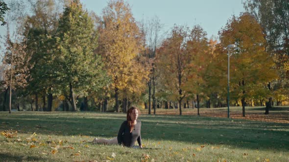 Young Woman Arching Backward in Autumn City Park on a Yoga Mat on a Sunny Day