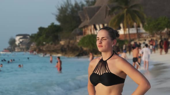 Young Beautiful Woman Stands on Exotic Beach and Looks Into the Distance Sunset