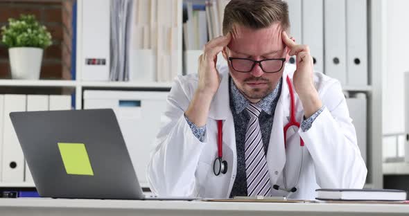 Tired Doctor Sitting in Front of Laptop and Massaging His Temple  Movie Slow Motion