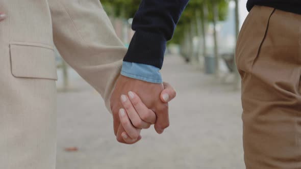 Close Up of Couple Holding Hands While Walking Outdoors