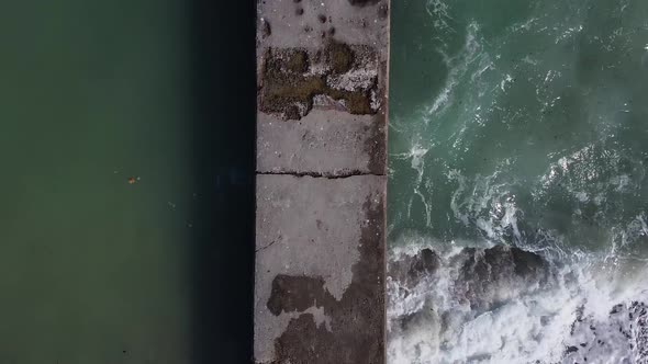 Aerial view drone flies over the sea along a concrete pier.