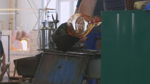 Employee Forms Hot Glass with Tool Over Tank with Water