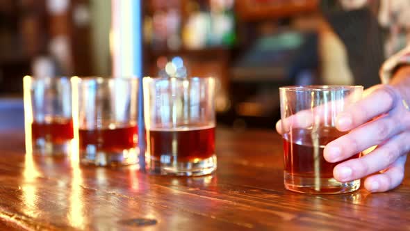 Mid section of barman serving whisky at bar counter