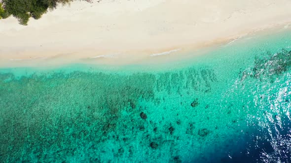 Aerial top down seascape of tranquil lagoon beach vacation by shallow ocean with white sand backgrou