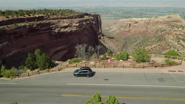 Drone flies over car near edge of large canyon in Colorado National Monument