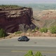 Drone flies over car near edge of large canyon in Colorado National Monument - VideoHive Item for Sale