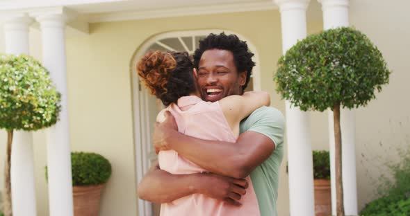 Happy biracial couple embracing with joy in front of new house