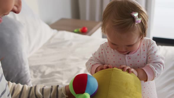 Caucasian mother and baby playing with toys on the bed at home