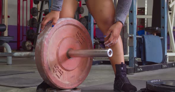 Female weight lifter adding weights to her lifting bar at the gym