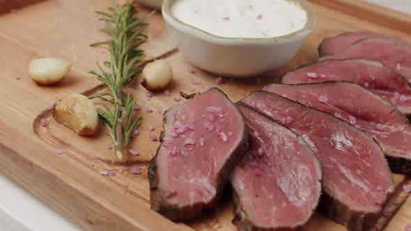 Grilled Rare Medium Beef Meat with Garlic and Rosemary in a Woden Plate