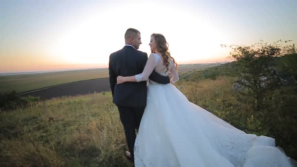 Bride and Groom Walking on the Grass Field in Love with Her Wedding Day