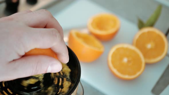 Man Squeezing Fresh Orange Fruit on a Juicer