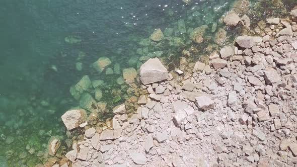 Zoom out of rocks in the ocean water of Torquay beach in England.