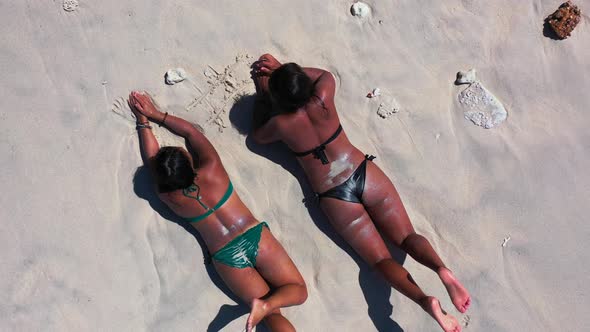 Young happy ladies on photoshoot spending quality time at the beach on sunny blue and white sand