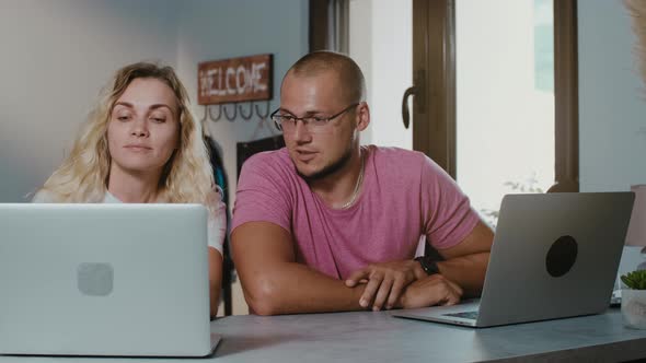 Young couple working together in coffee shop with laptop  browsing online