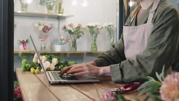 Unrecognizable Female Florist Typing On Laptop