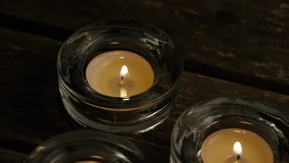 Tea candles with flaming wicks on a wooden background - CANDLES 025