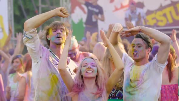 Young Smiling People Covered in Colorful Powder Dancing at Holi Festival Concert