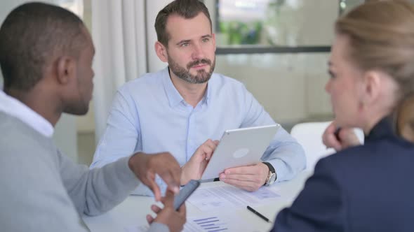 Male and Female Businessperson Talking While Holding Tablet in Office