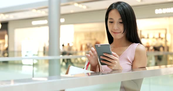 Woman use of mobile phone and carrying paper bags