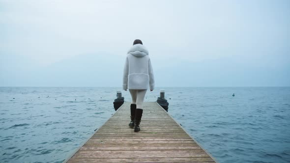 Woman Walks on Wooden Pier Enjoying Views of Lake Garda