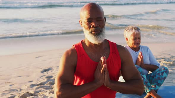 Senior african american couple practising yoga at the beach