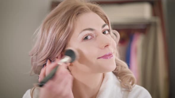 Close-up Face of Confident Caucasian Girl Applying Face Powder and Fixing Eyebrows. Smiling Young