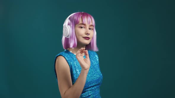 Attractive Modern Woman Dancing with Headphones on Blue Studio Background