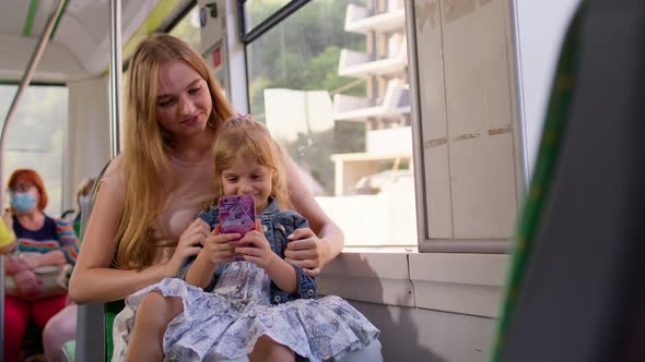 Child Girl with Mother Using Mobile Phone Internet Social Network Application While Traveling By Bus
