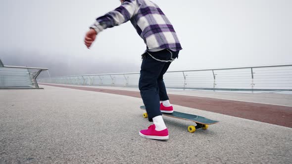 Close Portrait of Young Professional Skater Guy Performing Board Flip on City Bridge on Foggy