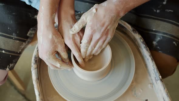 Slow Motion of Male and Female Hands Making Pot on Throwing Wheel Together