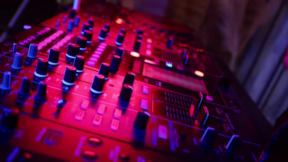 DJ Presses Buttons on Mixing Console with Which Music is Controlled in Nightclub at Party Closeup