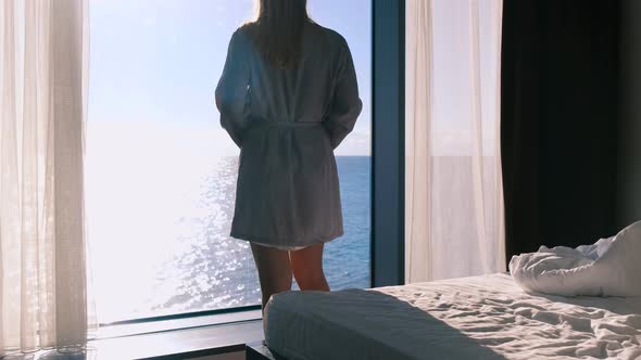 A Peaceful Happy Young Blonde in a Bathrobe Enjoys a Beautiful View of the Sea Standing Against the