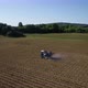 Aerial view of tractor spraying fertilizer on field at spring. Beautiful landscape in the background - VideoHive Item for Sale