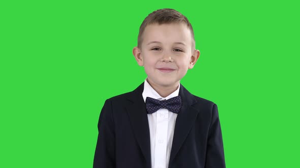 Smiling Little Boy in Formal Clothes Standing on a Green Screen, Chroma Key.