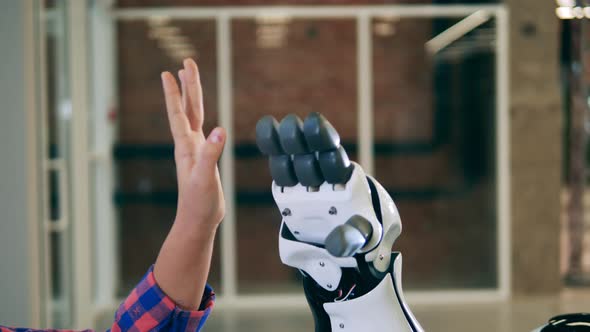 Close Up Shot of a Futuristic Robot Touching Hands with a Kid