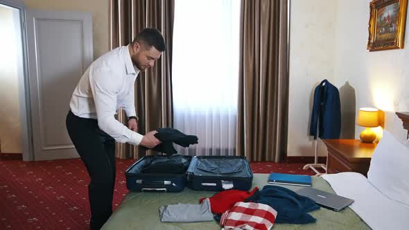 Businessman is packing luggage in hotel room.