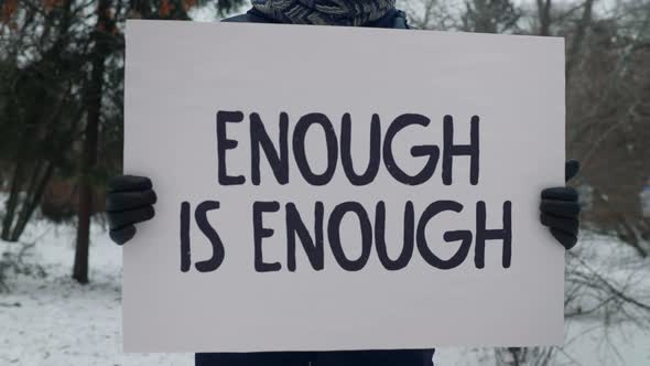 Man is expressing his oppinion on opression with a sign saying Enough Is Enough