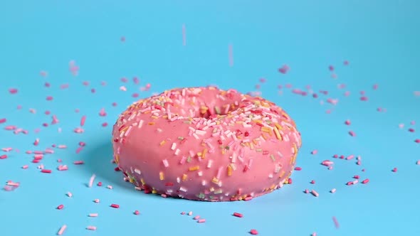 Color Toppings Sprinke on Top of Delicious Pink Donut on Blue Background. Sweet Food and Sugar