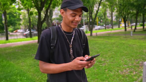 Smiling Guy Typing Message on Mobile Outdoors