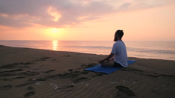 Man Sits in Lotus Position at Beach