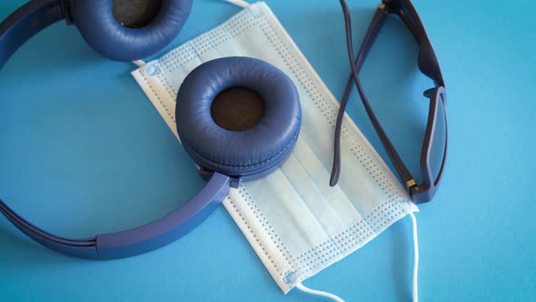 Face Mask Against Covid with Headphones and Sunglasses on Blue Background