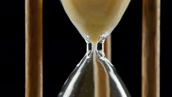 Hourglass Is Ticking. Yellow Sand. Black. Close Up