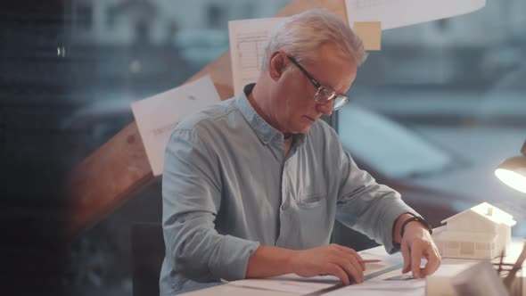 Senior Male Architect Drawing Construction Plan on Paper at Office Desk