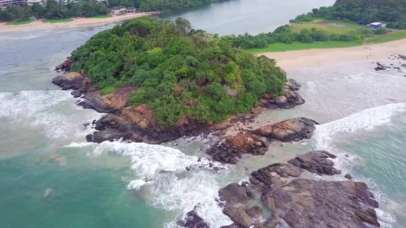 Waves Break on Dark Rocks Near Beach