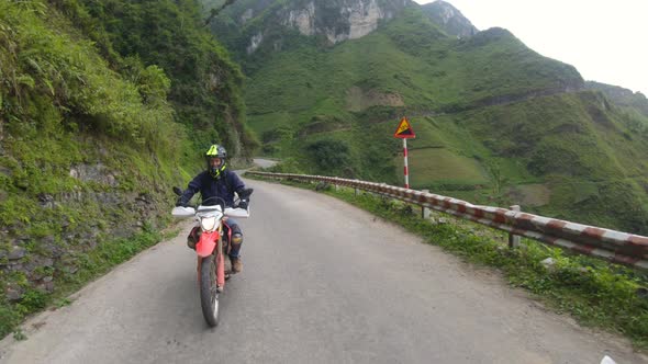 Man rides motorcycle along the Ma Pi Leng Pass.  Slow Motion. Northern Vietnam.