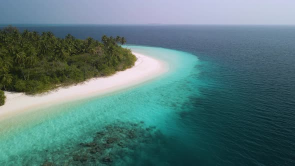 Incredible view of a beautiful Maldivian island with green trees, white sand and turquoise water