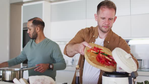 Multi ethnic male same sex couple preparing food together in kitchen