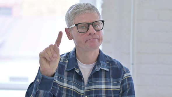 Portrait of Middle Aged Male Designer Saying No By Finger Sign